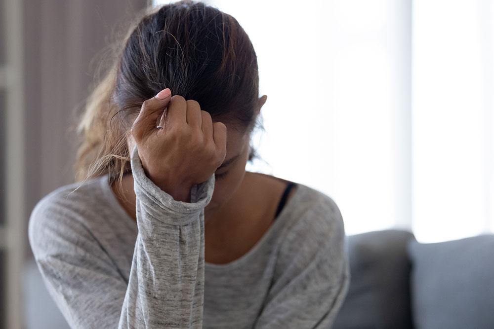 A woman rests her forehead on her palm, representing the need for anxiety therapy in Buckhead, GA.