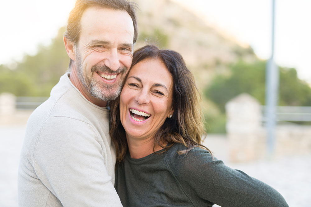 A smiling couple embraces at a park. This image represents the joy you can feel from couples counseling in Buckhead, GA.