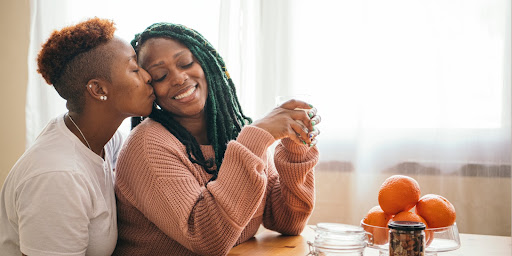 Romantic lesbian couple sitting at the dining table. This image symbolizes the bond that Atlanta premarital counseling can help you create with a new marriage partner.