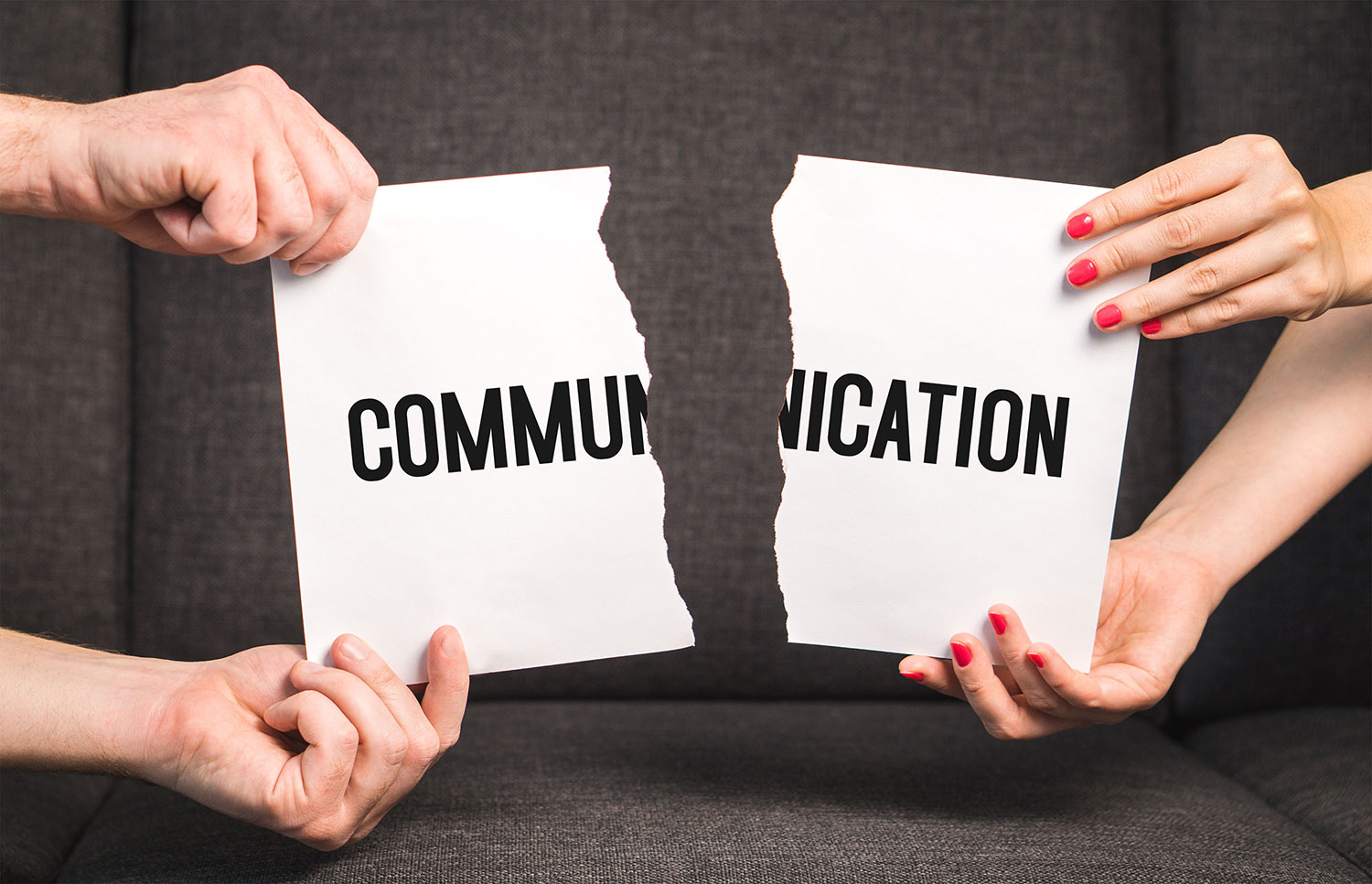 In this striking image, two individuals passionately tear apart a paper bearing the word "communication." Their intense actions symbolize the challenges faced in relationships, particularly in the context of Atlanta marriage counseling, where the mending and rebuilding of communication bridges are often a central focus. The torn paper serves as a poignant metaphor for the process of repairing and strengthening the lines of communication between couples in need of support and guidance.