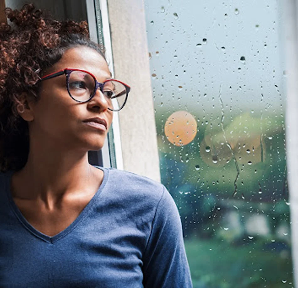 Woman looking out rainy window