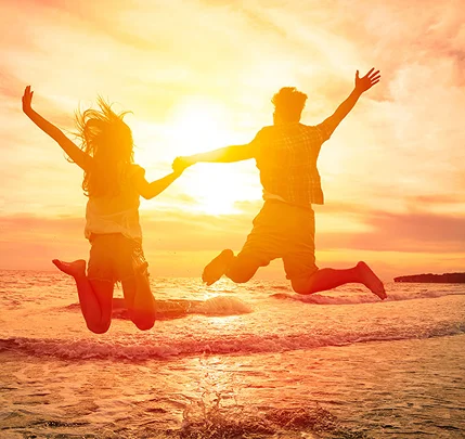 Couple jumping at sunset beach
