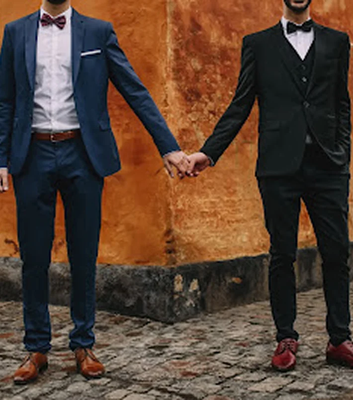Two men holding hands in suits
